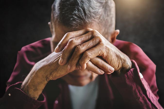 older male with head on hands looking sad and frustrated